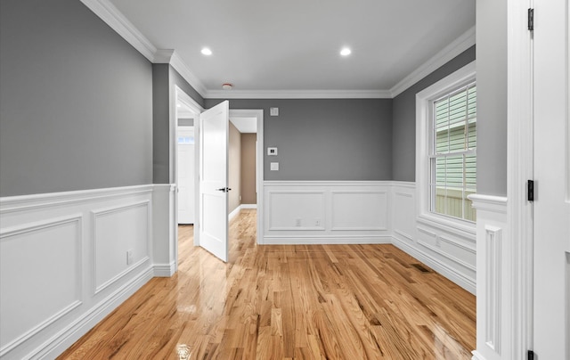 empty room with ornamental molding, recessed lighting, a wainscoted wall, and light wood-style flooring