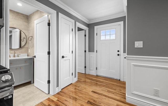 entryway with a wainscoted wall, light wood-style flooring, and crown molding