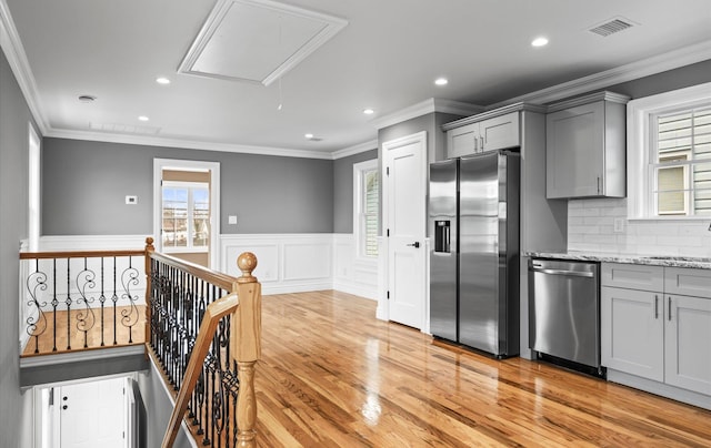 kitchen featuring visible vents, wainscoting, light wood-style flooring, gray cabinets, and stainless steel appliances