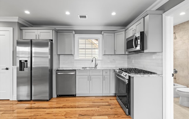 kitchen featuring visible vents, appliances with stainless steel finishes, gray cabinets, and a sink