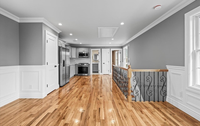 interior space with attic access, light wood-style floors, ornamental molding, and plenty of natural light