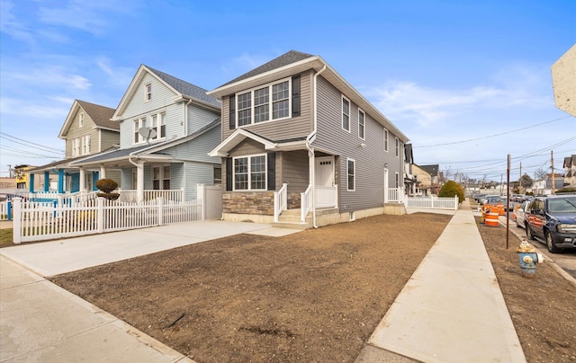 view of front facade featuring stone siding and fence