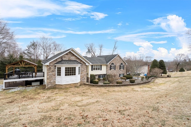 view of front of house featuring a gazebo, a front yard, stone siding, and a chimney