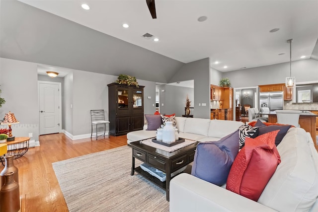 living area featuring visible vents, baseboards, vaulted ceiling, recessed lighting, and light wood-style flooring