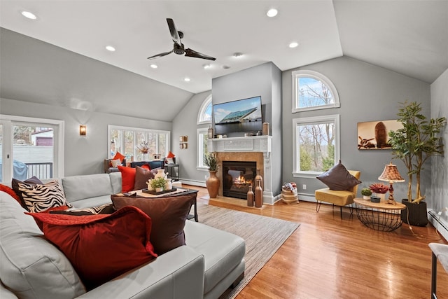 living area featuring a glass covered fireplace, baseboard heating, lofted ceiling, and wood finished floors