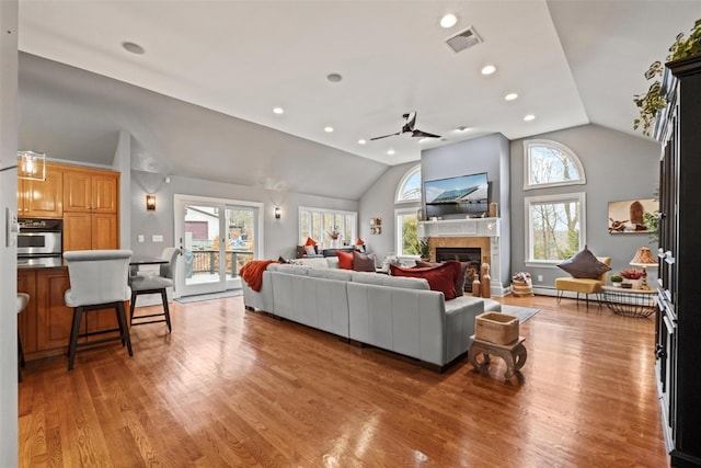 living area with recessed lighting, visible vents, a glass covered fireplace, and light wood-style flooring