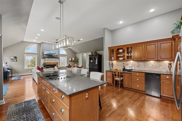 kitchen with dishwashing machine, wood finished floors, brown cabinets, a fireplace, and open floor plan