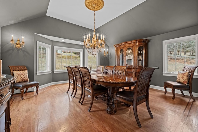 dining space with light wood-type flooring, an inviting chandelier, baseboards, baseboard heating, and vaulted ceiling