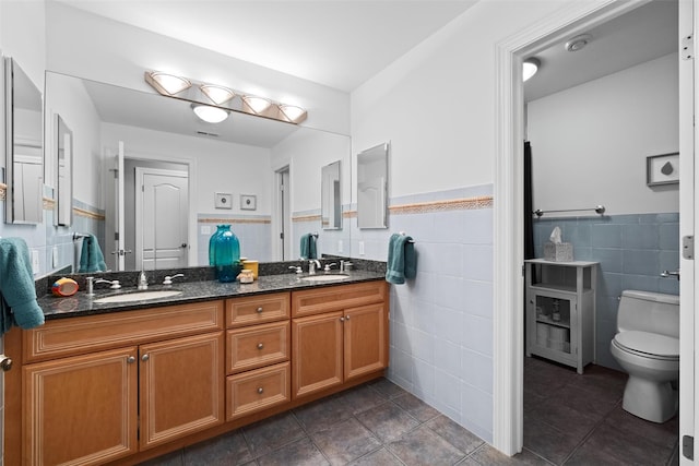 bathroom with a sink, toilet, and tile walls