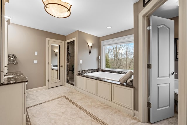 bathroom with baseboards, a garden tub, and vanity