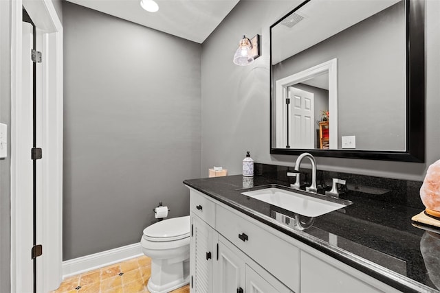 bathroom featuring visible vents, toilet, vanity, and baseboards