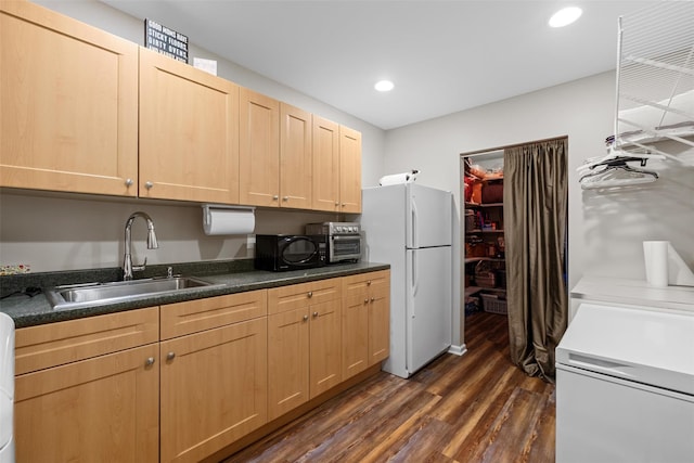 kitchen featuring light brown cabinetry, a sink, dark wood-style floors, freestanding refrigerator, and black microwave