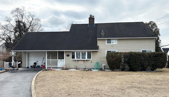 view of front of home with a garage, driveway, a shingled roof, a chimney, and a porch