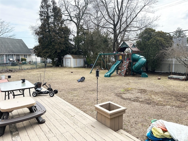 deck with an outbuilding, playground community, fence, and a storage unit