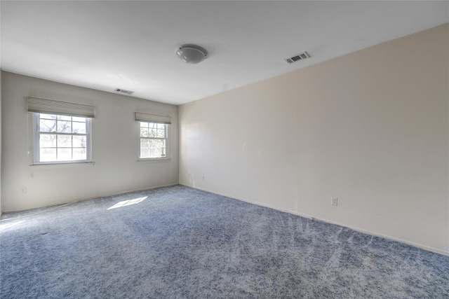 carpeted empty room featuring visible vents