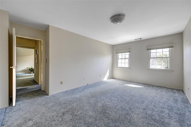 carpeted empty room featuring visible vents