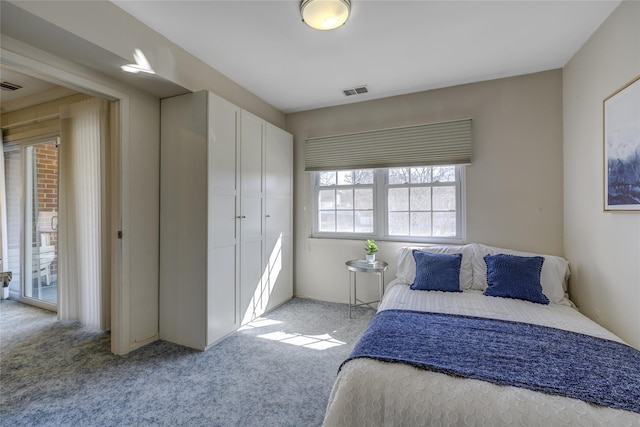 bedroom with a closet, light colored carpet, and visible vents