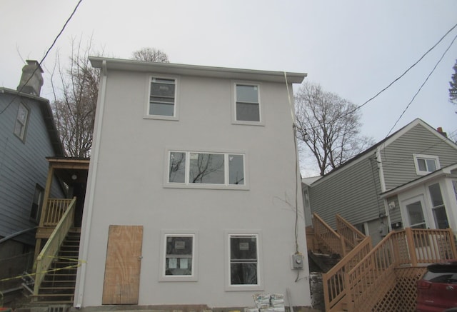 back of house with stairs and stucco siding