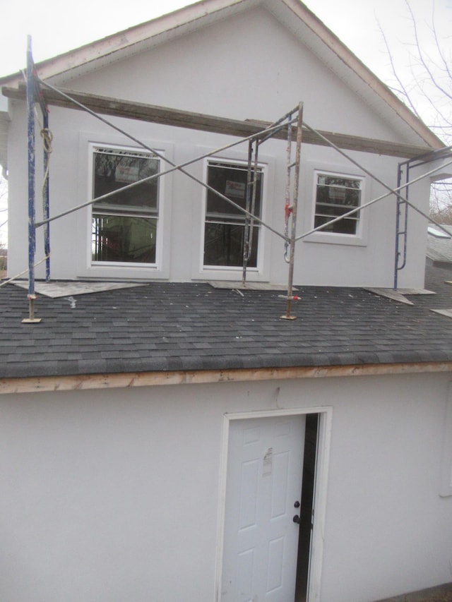 view of property exterior with a shingled roof and stucco siding