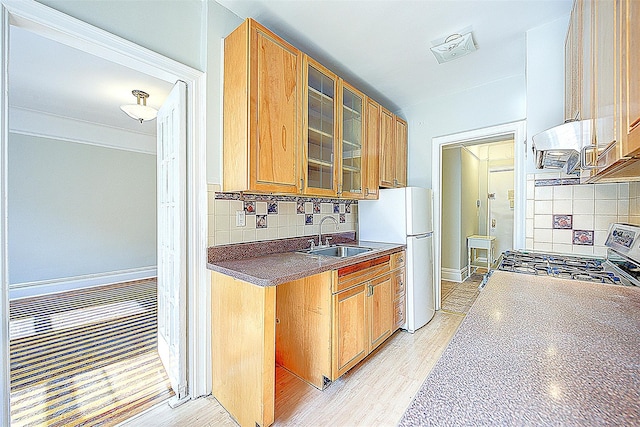 kitchen featuring stainless steel gas range oven, glass insert cabinets, backsplash, and a sink