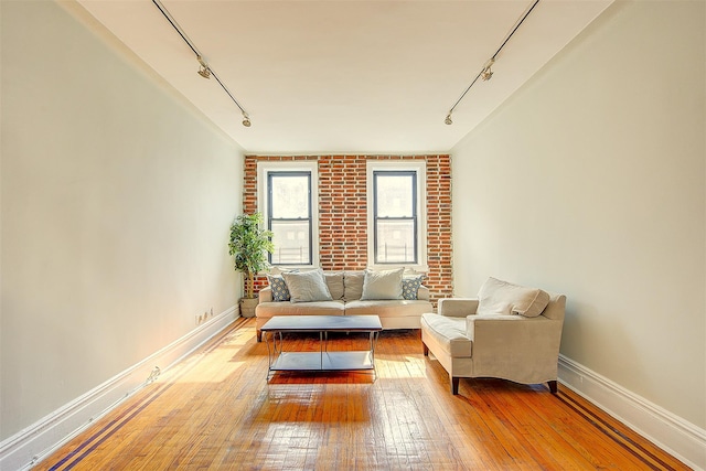 sitting room with rail lighting, baseboards, and hardwood / wood-style flooring