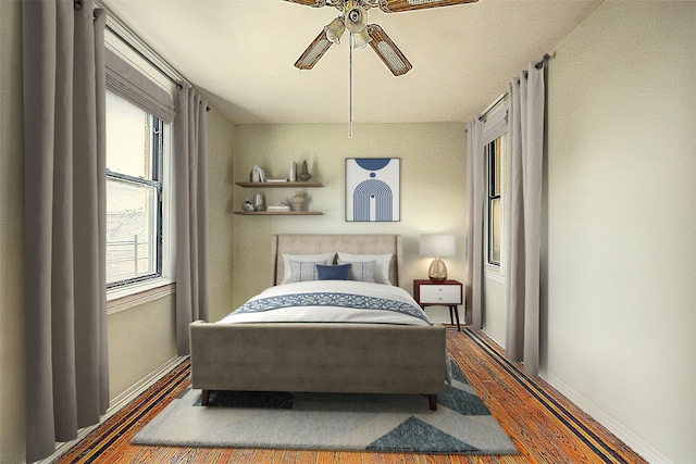 bedroom with ceiling fan, baseboards, and wood finished floors