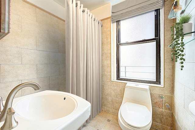 bathroom with toilet, tile walls, a sink, and a shower with shower curtain