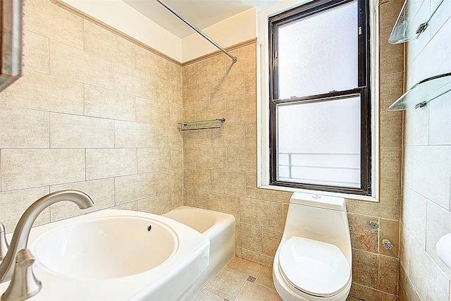 bathroom featuring toilet, a sink, and tile walls