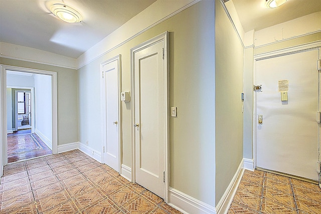 hall featuring baseboards and light tile patterned flooring