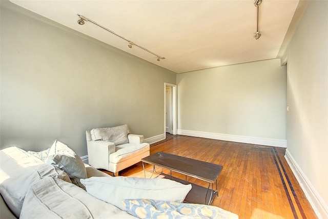 living area with rail lighting, hardwood / wood-style floors, and baseboards
