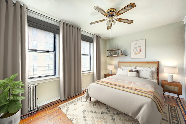 bedroom featuring wood finished floors, radiator heating unit, baseboards, and a ceiling fan