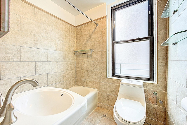 bathroom featuring healthy amount of natural light, toilet, tile walls, and a sink