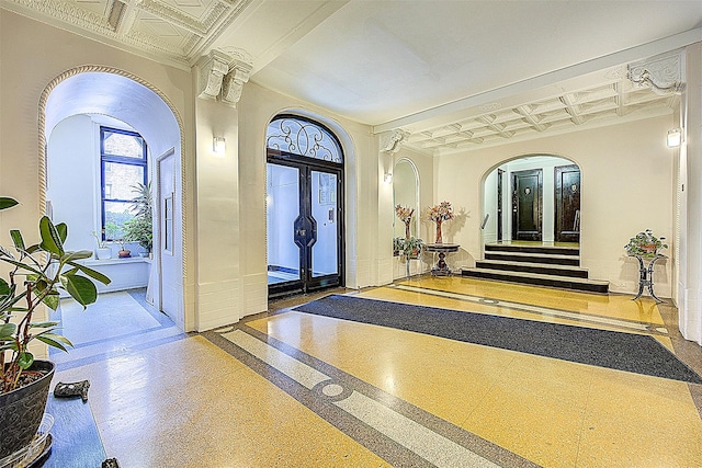 foyer featuring an ornate ceiling, baseboards, arched walkways, inlaid floor details, and coffered ceiling