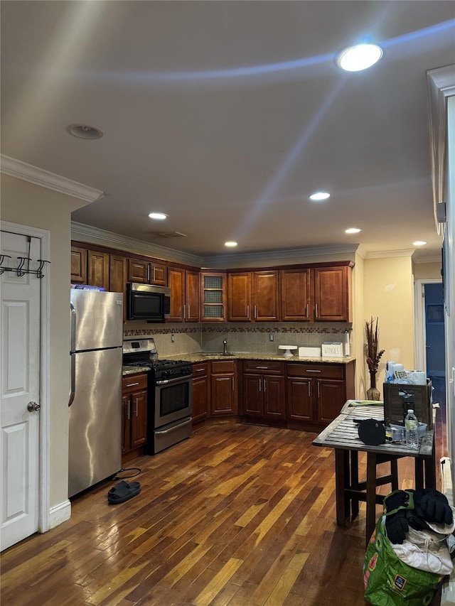 kitchen featuring crown molding, stainless steel appliances, decorative backsplash, dark wood-type flooring, and light stone countertops