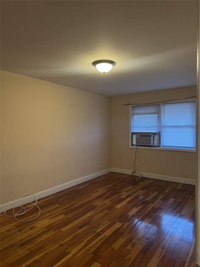 empty room featuring dark wood-type flooring, cooling unit, and baseboards