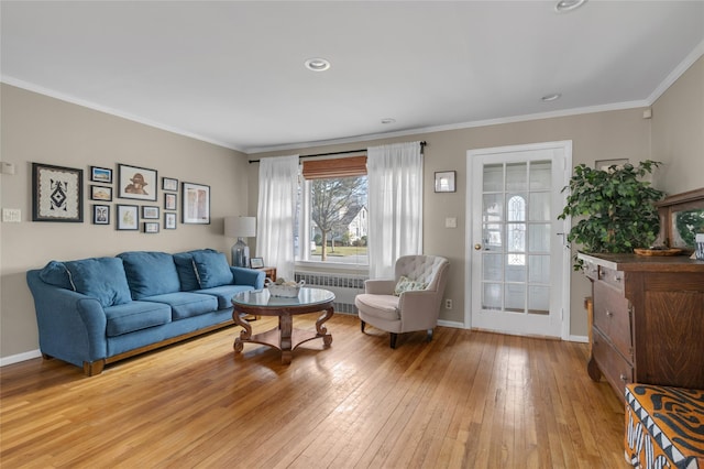 living area featuring radiator heating unit, baseboards, wood-type flooring, and ornamental molding