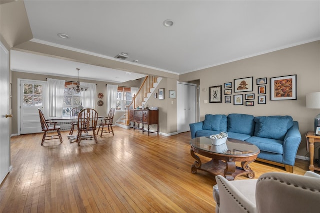 living area featuring light wood finished floors, stairway, crown molding, and baseboards