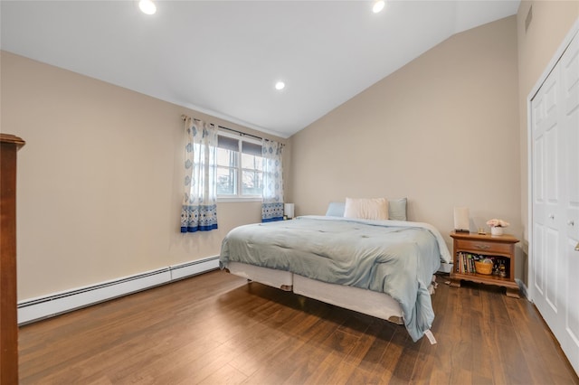 bedroom with a baseboard heating unit, lofted ceiling, a closet, and wood finished floors