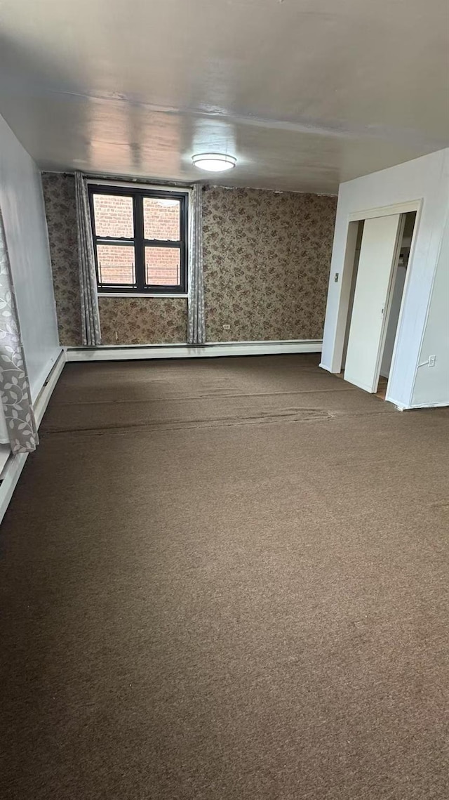 unfurnished room with dark colored carpet and wallpapered walls