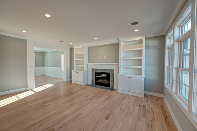 unfurnished living room featuring a healthy amount of sunlight, a fireplace, and crown molding