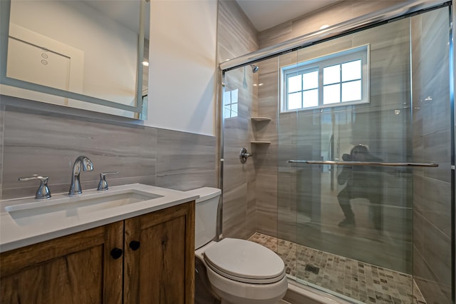 bathroom with a stall shower, tile walls, toilet, and vanity