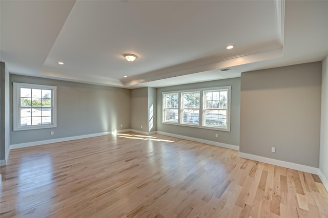 empty room with recessed lighting, a raised ceiling, visible vents, light wood-style floors, and baseboards