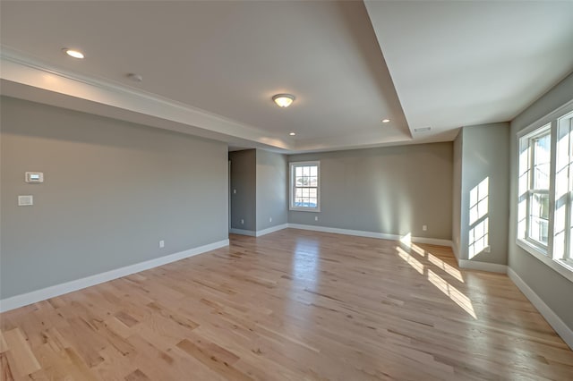 spare room with baseboards, a tray ceiling, light wood-style flooring, and recessed lighting