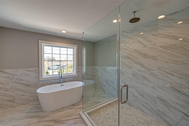 bathroom featuring a stall shower, marble finish floor, and a freestanding tub