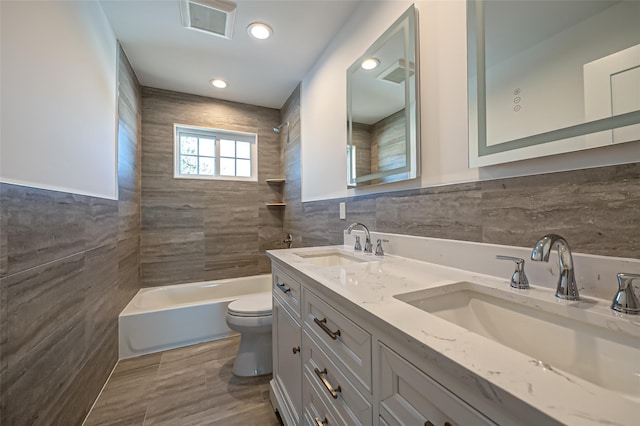 bathroom with toilet, tile walls, a sink, and bathing tub / shower combination