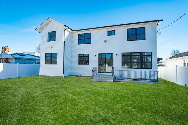 rear view of house with a fenced backyard and a lawn