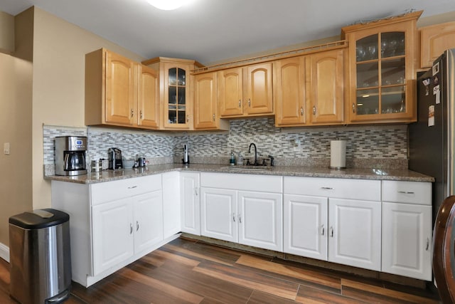 kitchen featuring decorative backsplash, light stone counters, dark wood finished floors, and a sink