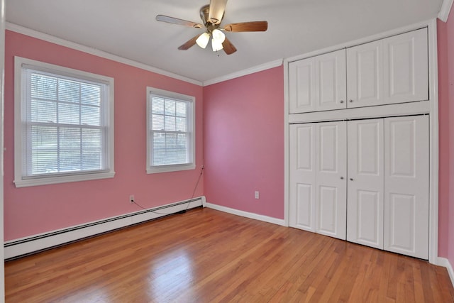 unfurnished bedroom with baseboards, light wood-style floors, ornamental molding, baseboard heating, and a closet