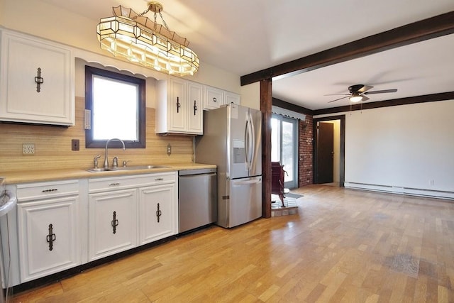 kitchen featuring stainless steel appliances, plenty of natural light, a baseboard heating unit, and a sink