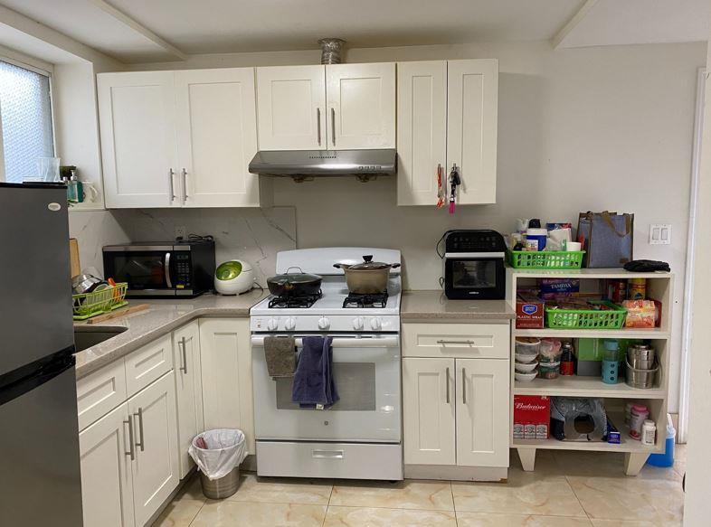 kitchen with appliances with stainless steel finishes, white cabinetry, under cabinet range hood, and light tile patterned floors